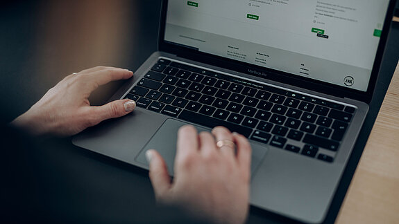 Person sitzt am Laptop und scrollt durch die ZAK-Website